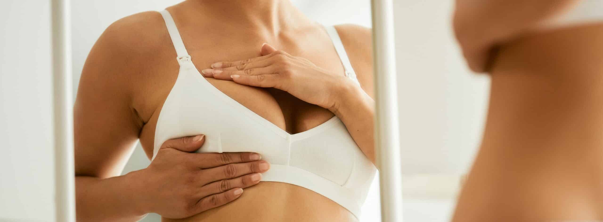 Poitrine d une femme la regardant dans le miroir Augmentation mammaire quelle technique choisir | Dr Christophe Reinbold Lyon