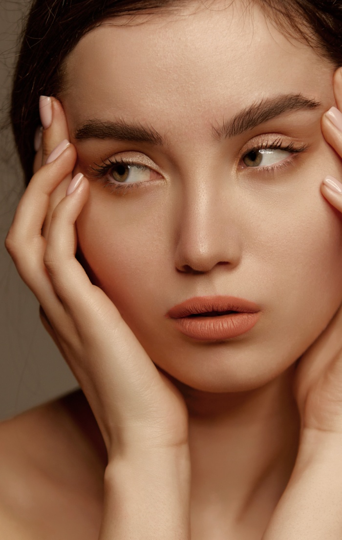 Photo stylisee du visage d une jeune femme qui pose sa main sur les coin des yeux lifting temporal | Dr Christophe Reinbold Lyon